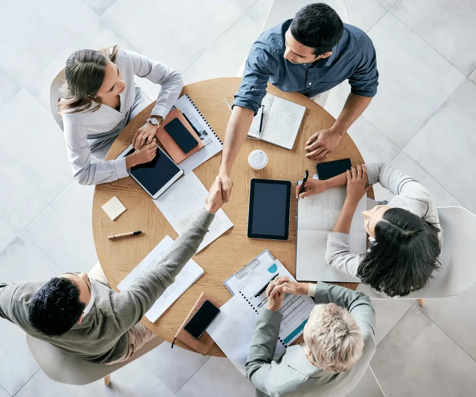 Business meeting with handshake around table.